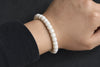 White bodhi seed mala bracelet worn on a wrist against a softly blurred dark background